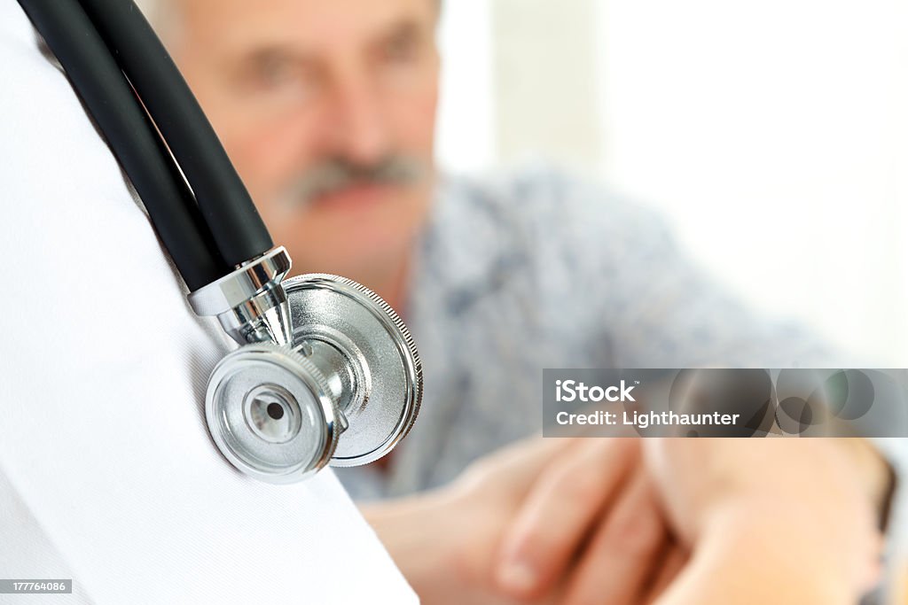 Medical Care Doctor holding eldery patient's hand carefully - focus on stethoscope. Adult Stock Photo