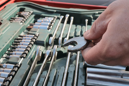 man holding an fixed wrench next to the tool cart