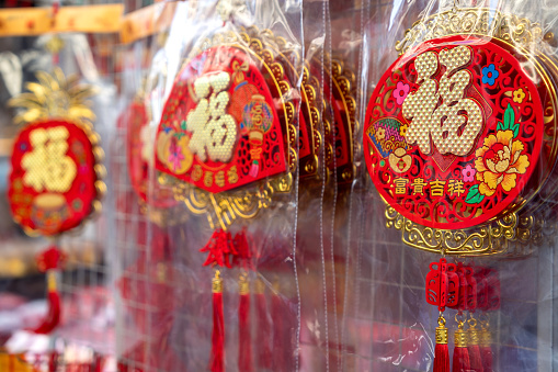 A vibrant array of decorations and ornaments for Chinese New Year, symbolizing luck, healthiness, happiness, reunion, and prosperity, is on display at a market stall for sale.