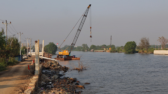 Under construction of concrete dam with heavy equipment at the mouth of the river