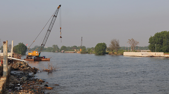 Under construction of concrete dam with heavy equipment at the mouth of the river