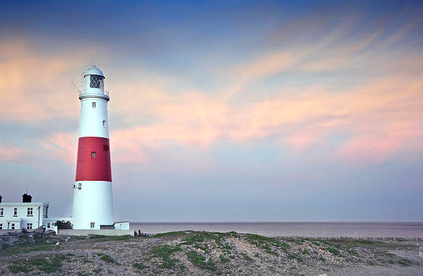 istock Victorian lighthouse on promontory of rocky cliffs at sunset 177767067