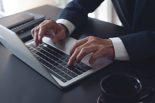 istock Businessman online working on laptop computer, surfing the internet, networking at modern office, closeup. Business man hand typing ob laptop computer keyboard on office desk 1777672274