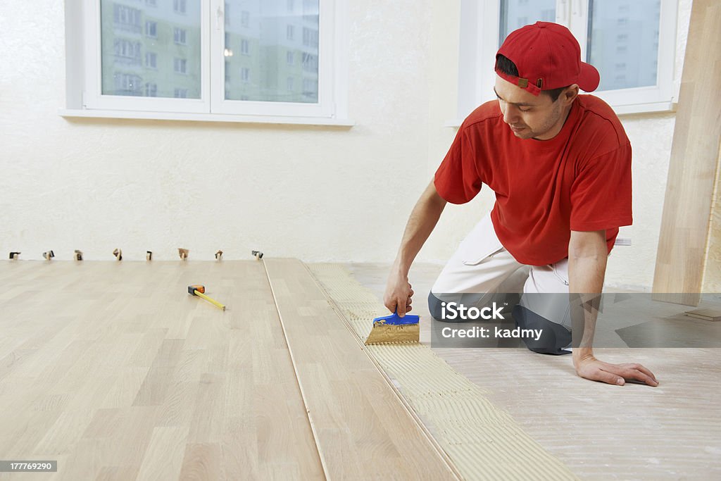 parquet worker adding glue on floor Handyman parquet carpenter worker adding glue on base during indoor wood flooring Adult Stock Photo