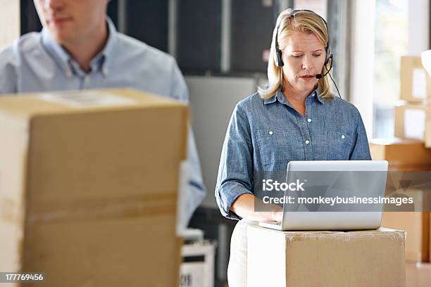 Female Manager Using Headset In Distribution Warehouse Stock Photo - Download Image Now