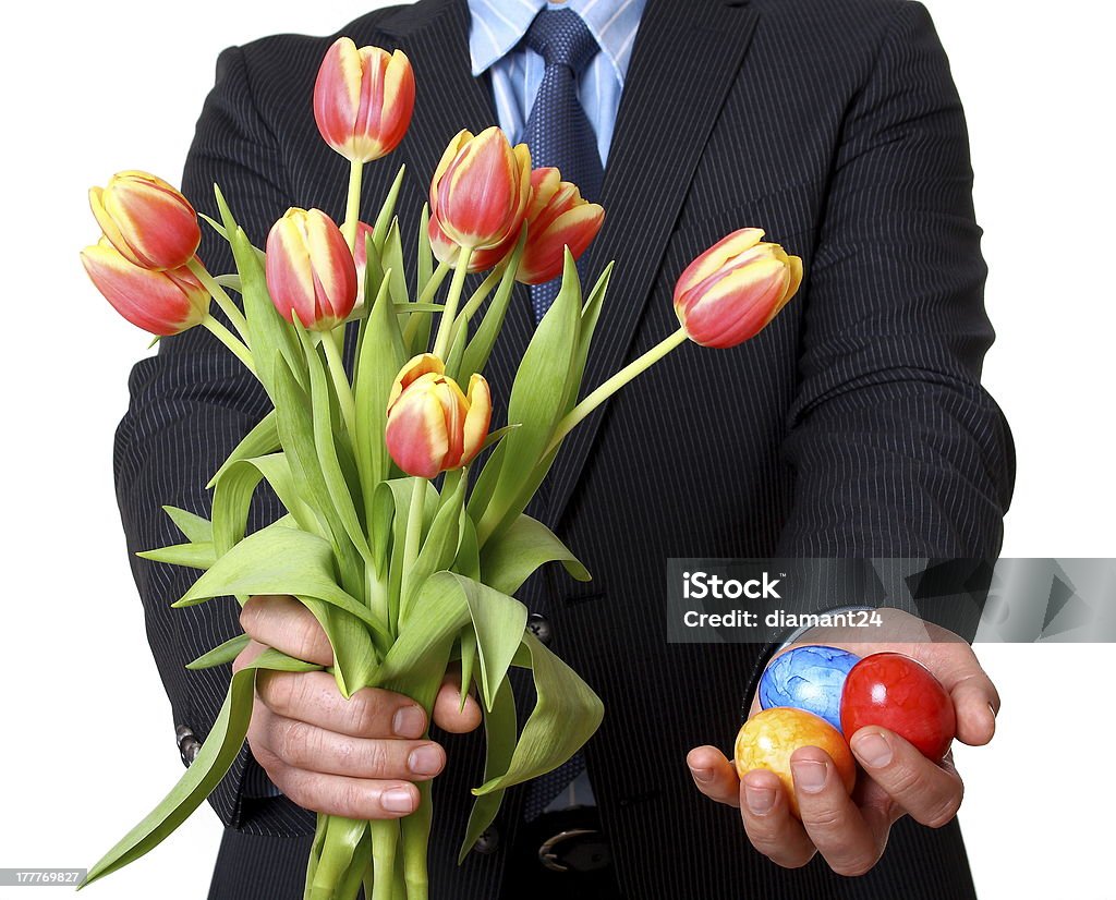 Man in suit with tie gives Easter eggs and tulips Man in suit with tie gives tulips and Easter eggs Adult Stock Photo
