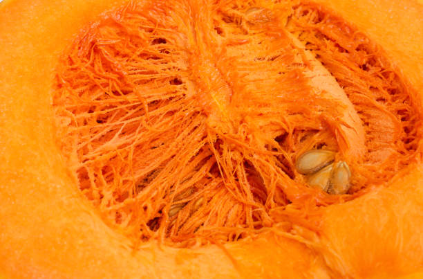 Pumpkin pulp with fibers and seeds close-up. Cut ripe bright orange pumpkin. Source of fiber, provitamin A, zinc, selenium, vitamin C. Low-calorie diet food