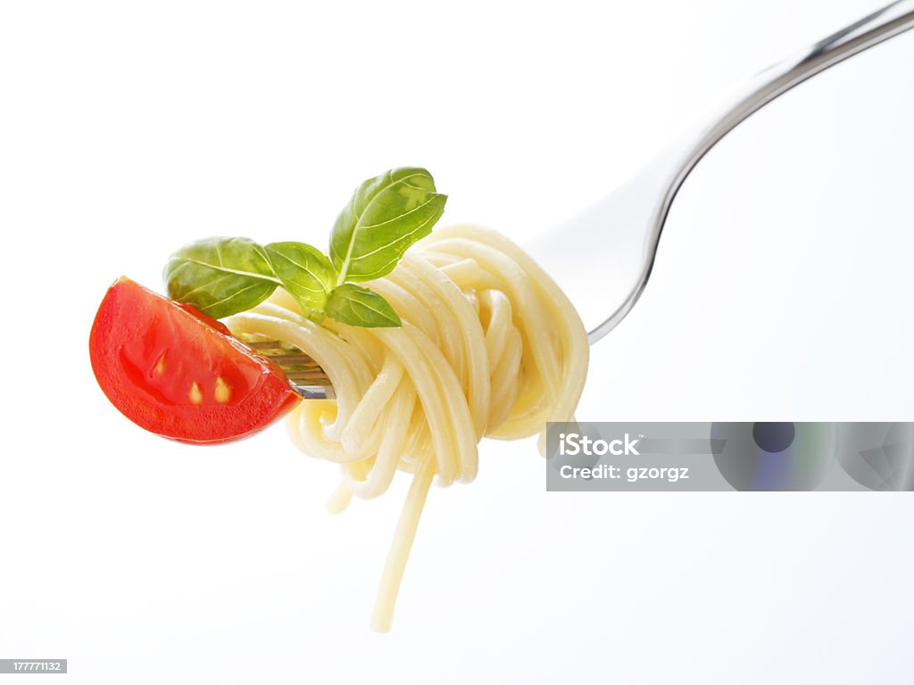 Spaghetti pasta with tomato and basil on fork Spaghetti with tomato and basil on fork, isolated on white background. Close-up shoot, shallow focus. Basil Stock Photo