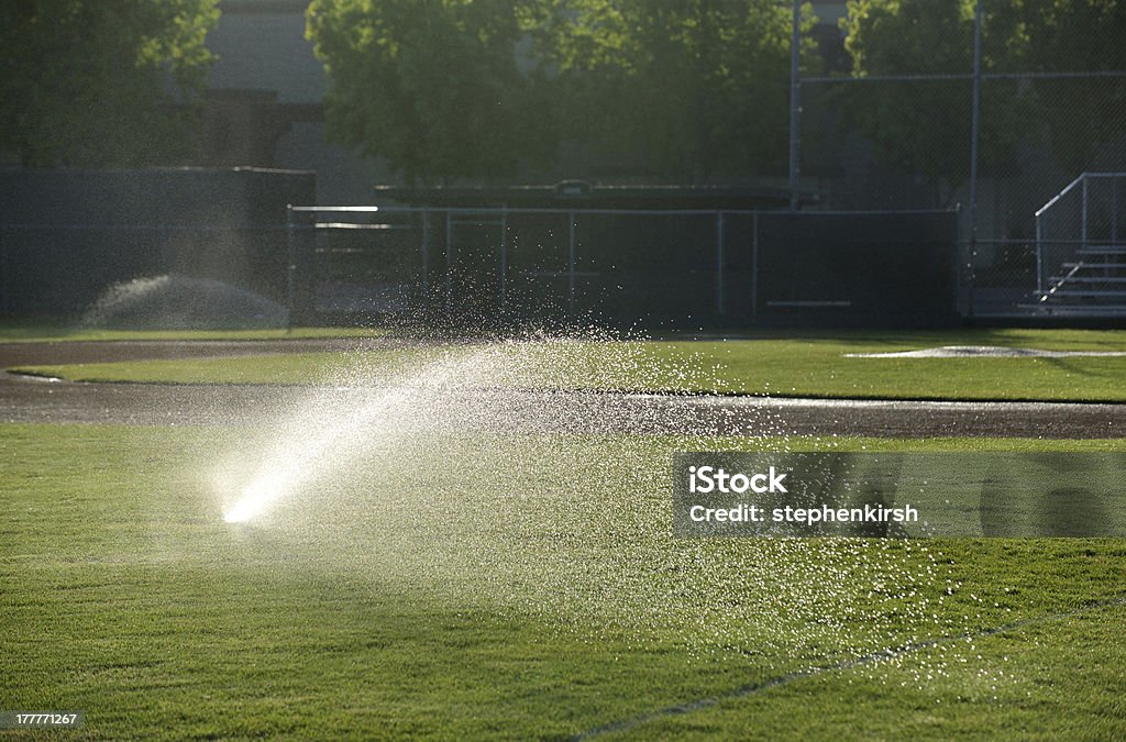 Baseball field sprinkler waters the grass, pointed right Agricultural Sprinkler Stock Photo