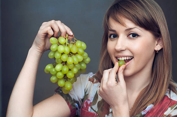 istock the smiling girl is eating  grapes 177771491