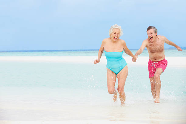istock Cute old white couple running through the water at a beach 177771528