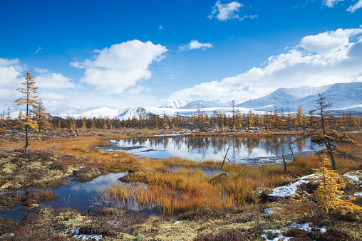 Russia. Magadan Region. Beautiful Lake Momontay against the backdrop of a snowy mountain range. Late autumn in the vicinity of Lake Momontay.