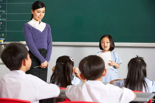 Photo of Pupil And Teacher Standing By Blackboard In Chinese School Classroom