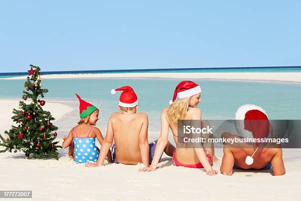 Family Sitting On Beach With Christmas Tree And Hats Stock Photo - Download Image Now