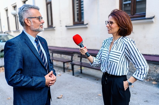 A female journalist with a microphone interviewing a businessman