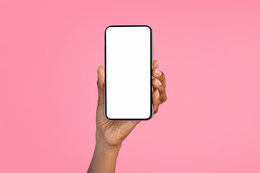 Hand of millennial black lady show smartphone with blank screen, isolated on pink background, studio, close up, cropped. App, website, gadget recommendation, sale, ad and offer