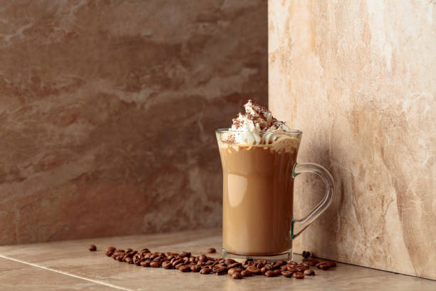 istock Glass cup of coffee latte on a beige ceramic table. 1777738526