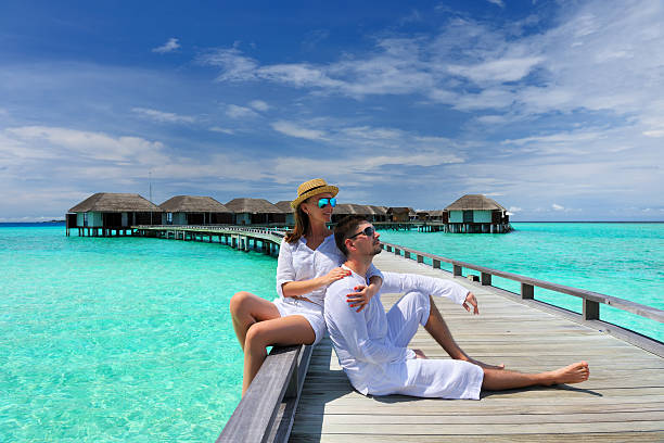 Couple on a beach jetty at Maldives stock photo