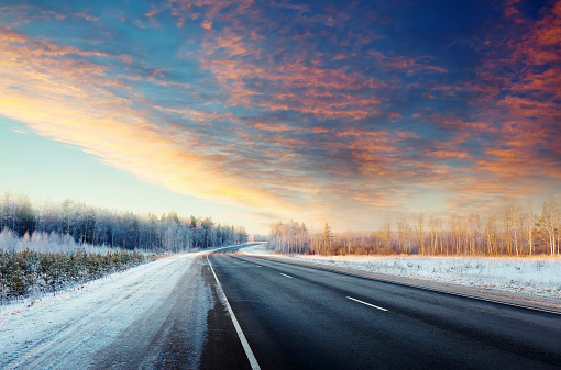 Winter road through snowy fields and forests