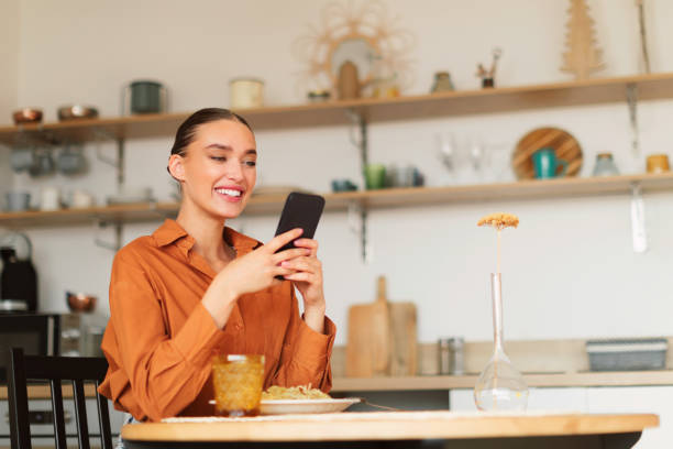 istock Cheerful caucasian lady sitting at table in kitchen and using cellphone, shopping online from home, copy space 1777755419