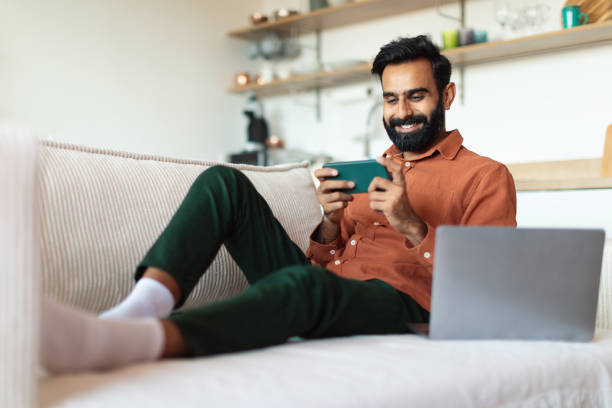 istock Bearded Indian Man Using Smartphone Sitting Near Laptop At Home 1777777840