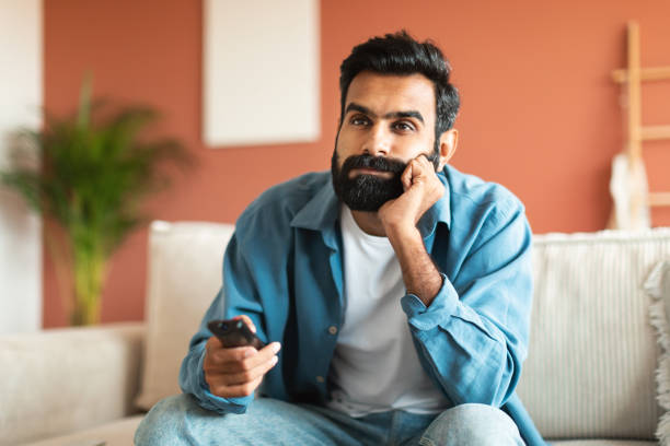 istock Middle eastern guy switching television channels sitting at home 1777779608