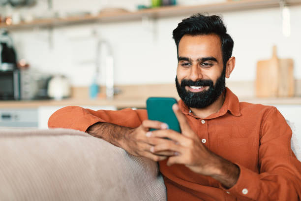 istock Happy Indian Bearded Guy Using Smartphone Texting At Home 1777780198