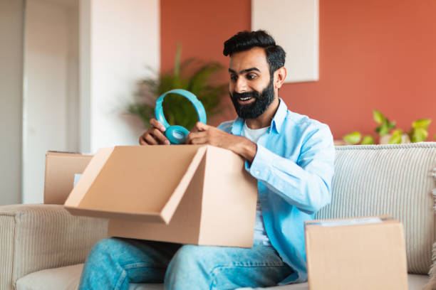 istock Cheerful middle eastern guy checking delivery package holding headphones indoor 1777780245