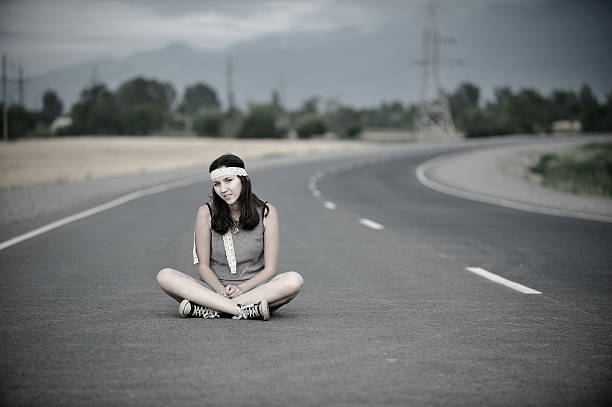 istock Girl with a head band sitting on road cross legged 177780980