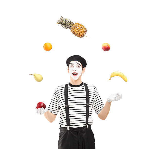 Smiling mime artist juggling fruits A smiling mime artist juggling fruits isolated against white background mime artist stock pictures, royalty-free photos & images