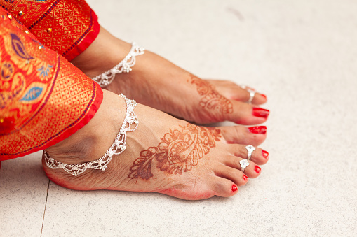Indian Wedding Concept. Beautiful feet of an Indian bride, decorated with auspicious Mehndi, anklets, and toe rings.