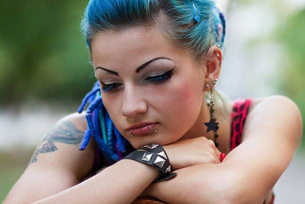 Sad punk girl posing outdoors Sad but beautiful punk girl sitting outdoors piercing stock pictures, royalty-free photos & images
