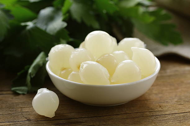 les petits oignons macérés perles sur une table en bois - oignon blanc photos et images de collection