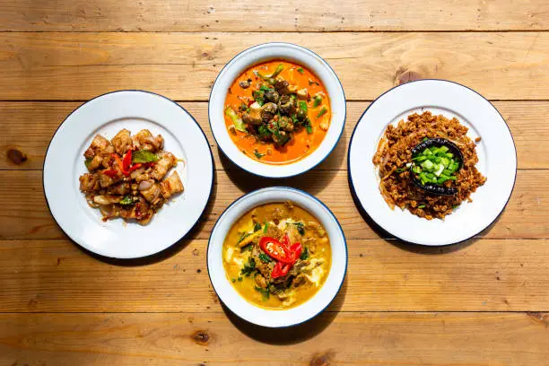 Photo of Top View Crispy Pork Belly with Chili and Salt and Curry with Beef Recipe and River snail red curry in red curry coconut milk soup and spicy minced pork salad (Larb Moo Kua). Thai food,