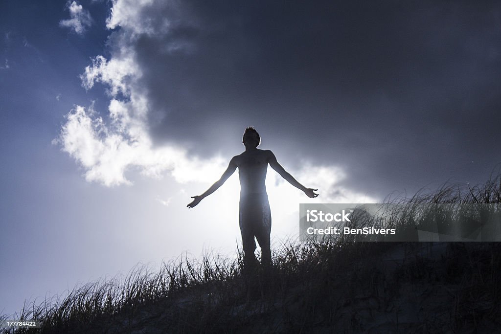 Man looking up with open arms Young Man looking up standing on hill with open arms Beach Stock Photo