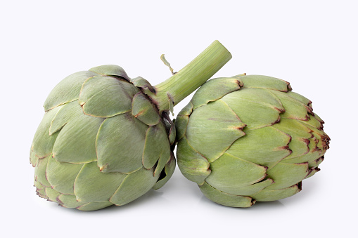 Close up view of fresh whole artichoke and halves shot from above on dark wood table. High resolution 42Mp studio digital capture taken with SONY A7rII and Zeiss Batis 40mm F2.0 CF lens