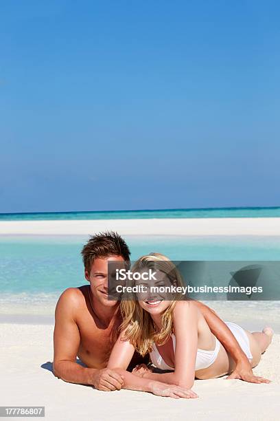 Pareja Disfrutando De Vacaciones En La Playa Foto de stock y más banco de imágenes de 20 a 29 años - 20 a 29 años, Abrazar, Acostado