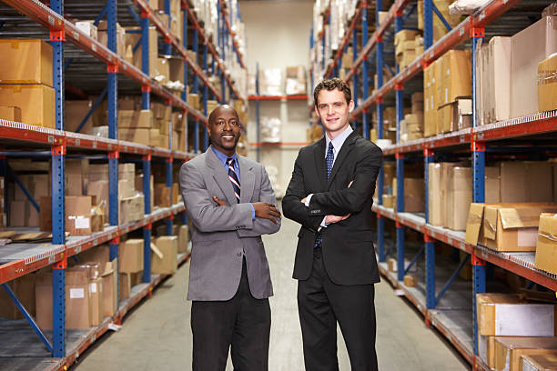 Portrait Of Two Businessmen In Warehouse In Suits Smiling