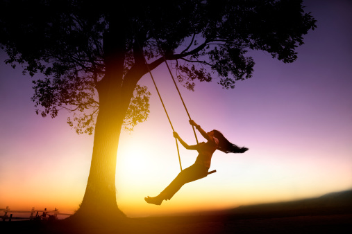 silhouette of young woman on a swing