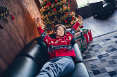 Photo of nice young pretty girl lying leather couch hands up wake up dreamy sleeping good morning winter hotel xmas tree decor background