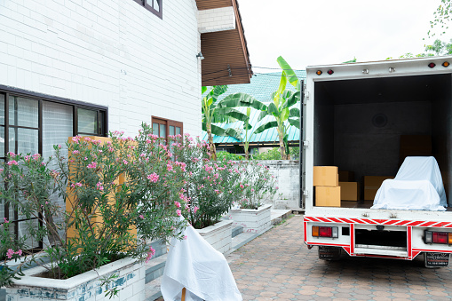 Delivery truck stop in front of new house full of packages and cardboard box and furniture prepared to send to customer, moving house services company, shipping small business entrepreneurship