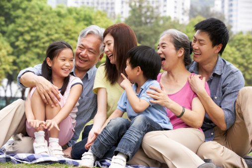 Portrait Of Multi-Generation Chinese Family Relaxing In Park Together Looking At Each Other Talking