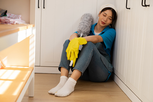 Two Asian maid female in services company team working at customer's house tired after overwork sleeping at workplace, unqualified workers labor with household cleaning equipment napping while working