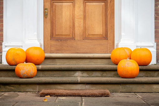 An arrangement of pumpkins outside a house at Halloween.