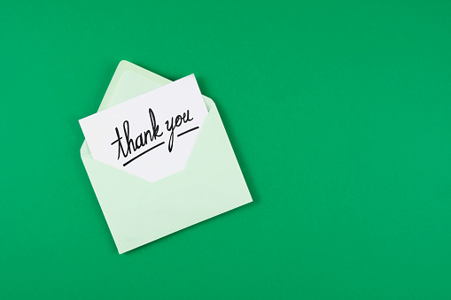 Opened envelope with thank you message on green colored background