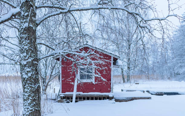 paesaggio invernale con una casa di legno rossa nel mezzo di un campo innevato - winter finland agriculture barn foto e immagini stock