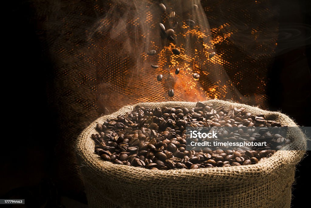 Chicchi di caffè che cade al sacco pieno di fumo caffè. - Foto stock royalty-free di Borsa