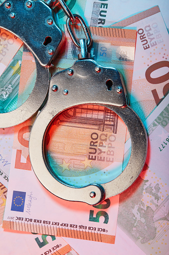 Handcuffs and euro banknotes under colorful police lights