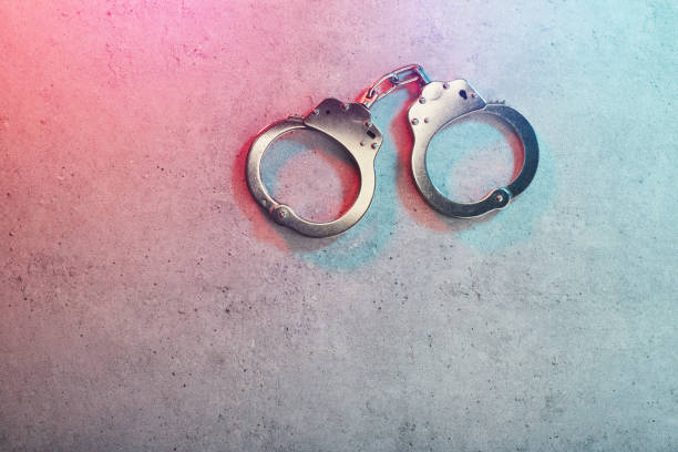istock Handcuffs on concrete surface with police vehicle lighting 1777955026