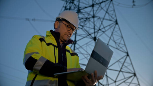 istock Mature Male Engineer Using Laptop Against Electricity Pylon And Blue Sky 1777961257